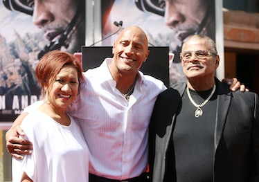 Dwayne Johnson is on a red carpet with his mother to his left and his late dad, Rocky Johnson, to hi...