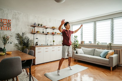 A man doing jumping jacks exercise at home.