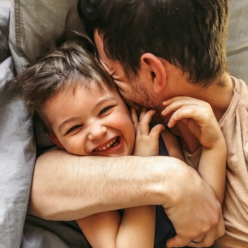 A dad and his son cuddling and smiling.