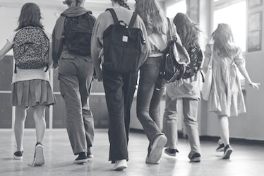 Back view of six high school students walking in a school corridor.