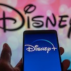 Disney + streaming icon displayed on smartphone with Walt Disney seen in the background. On 12 Augus...