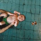 A dad in ISR swim lessons helping his baby float on their back.