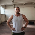 A man in a gym power posing with his hands on his hips.