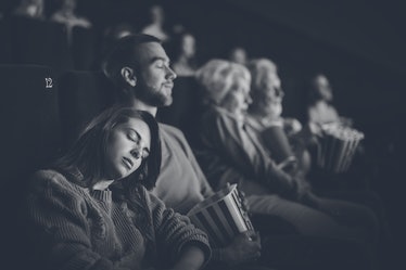 Young couple fell asleep during a boring movie in cinema. Focus is on woman.