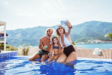 Family in swimsuits taking a selfie on the edge of a pool