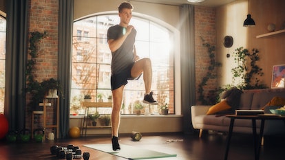 A man does high knees exercise at home on yoga mat.