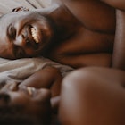 Man grinning in bed as he talks to his wife